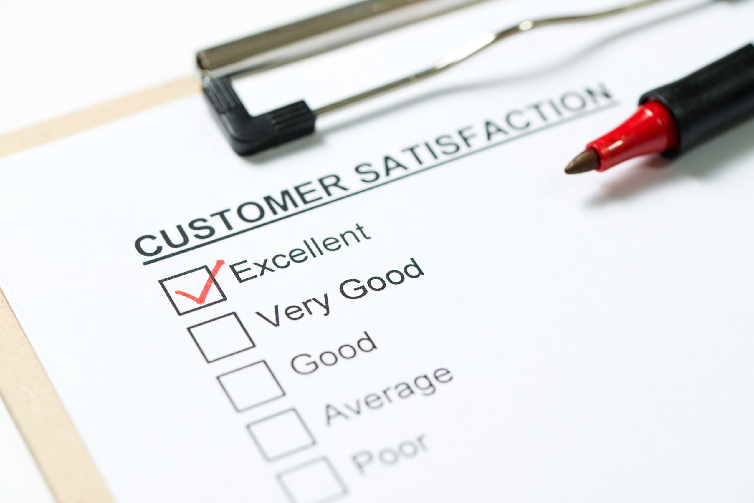 Customer satisfaction survey form on clipboard with red pen