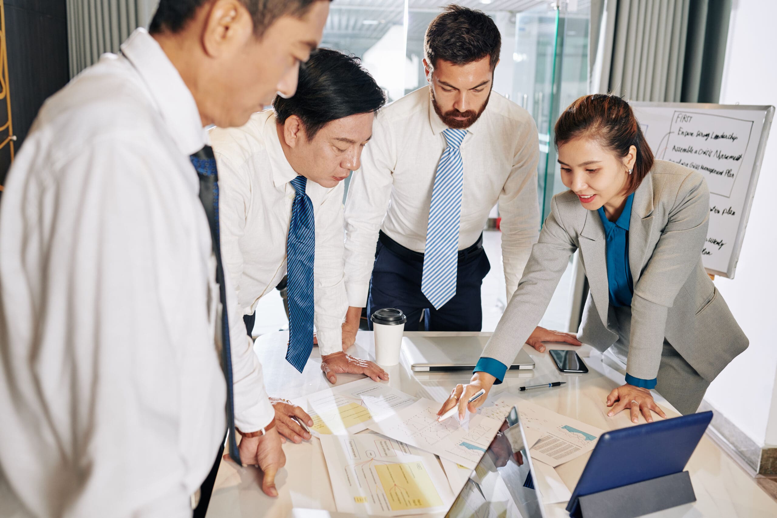 Positive female entrepreneur showing charts and diagrams to colleagues when discussing strategy of development at meeting