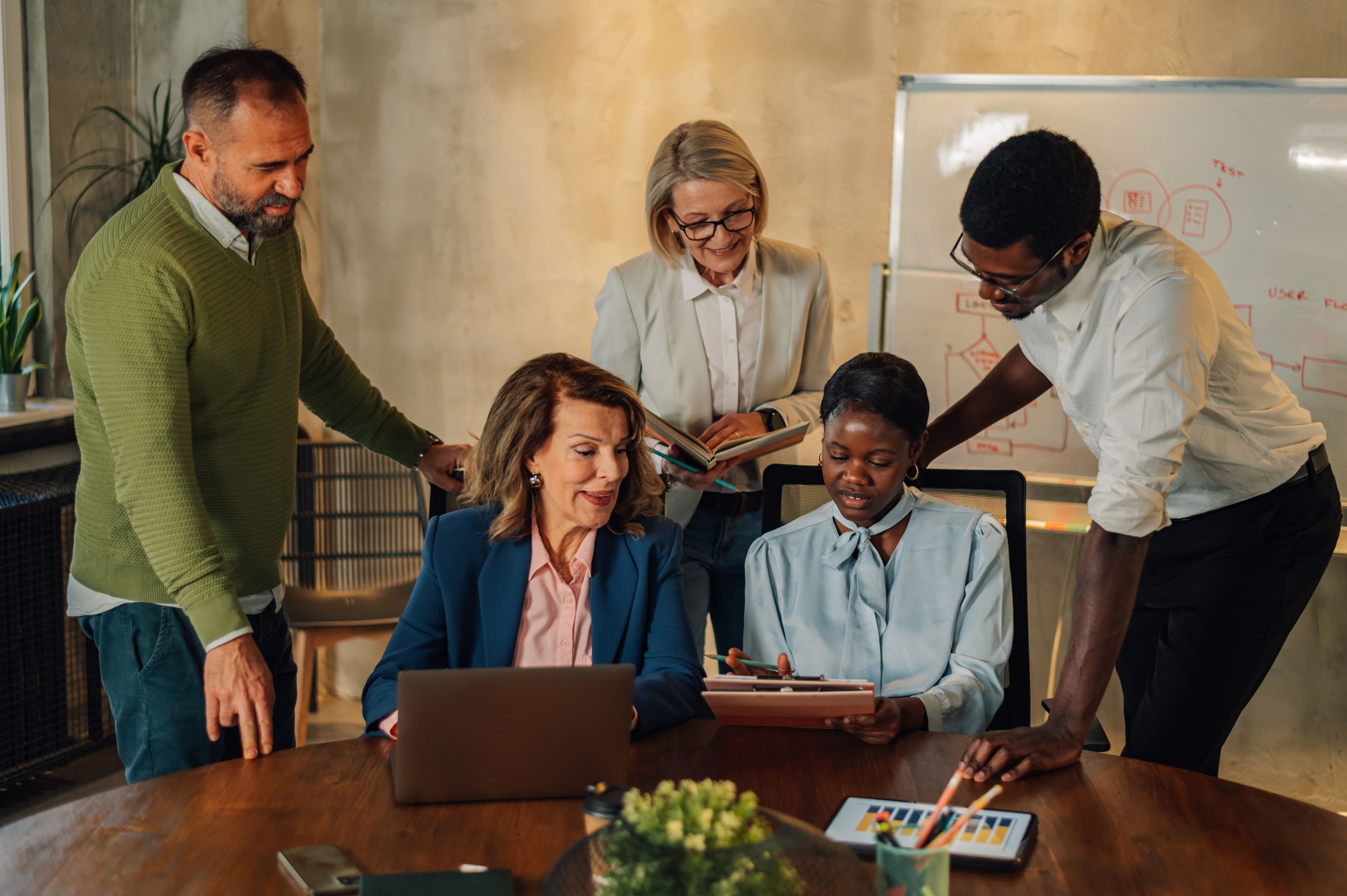 Portrait of a diverse business team working together at corporate briefing gathered at table in the conference room. Creative diverse colleagues in a boardroom discussing business together. Copy space